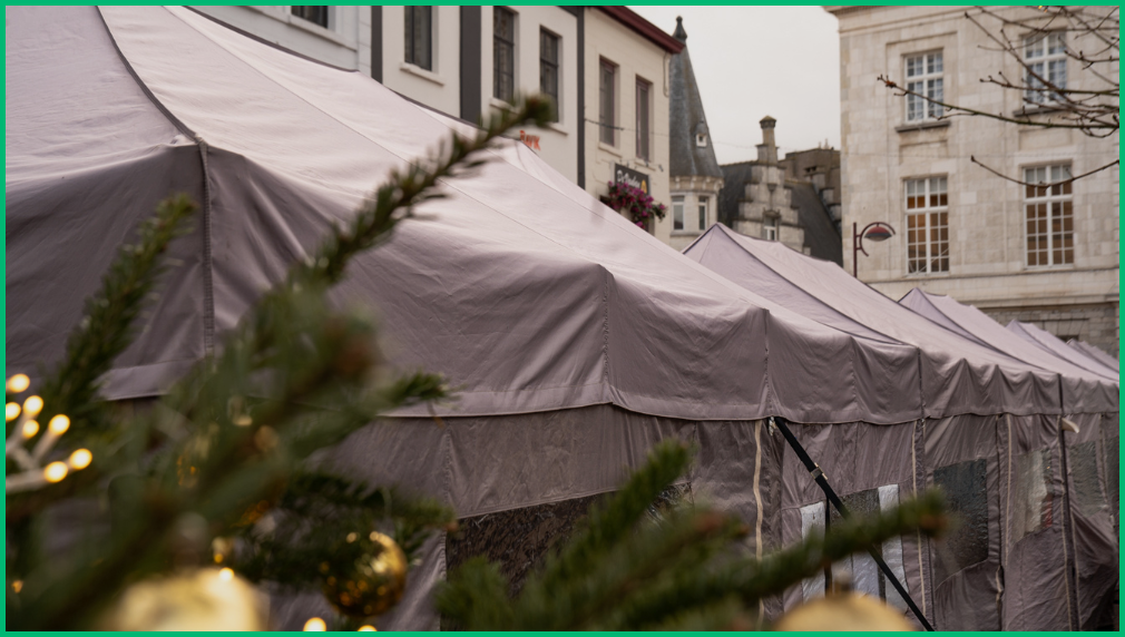 Grijze evenemententent op kerstmarkt fotografisch door groene kerstboom met gouden decoratie