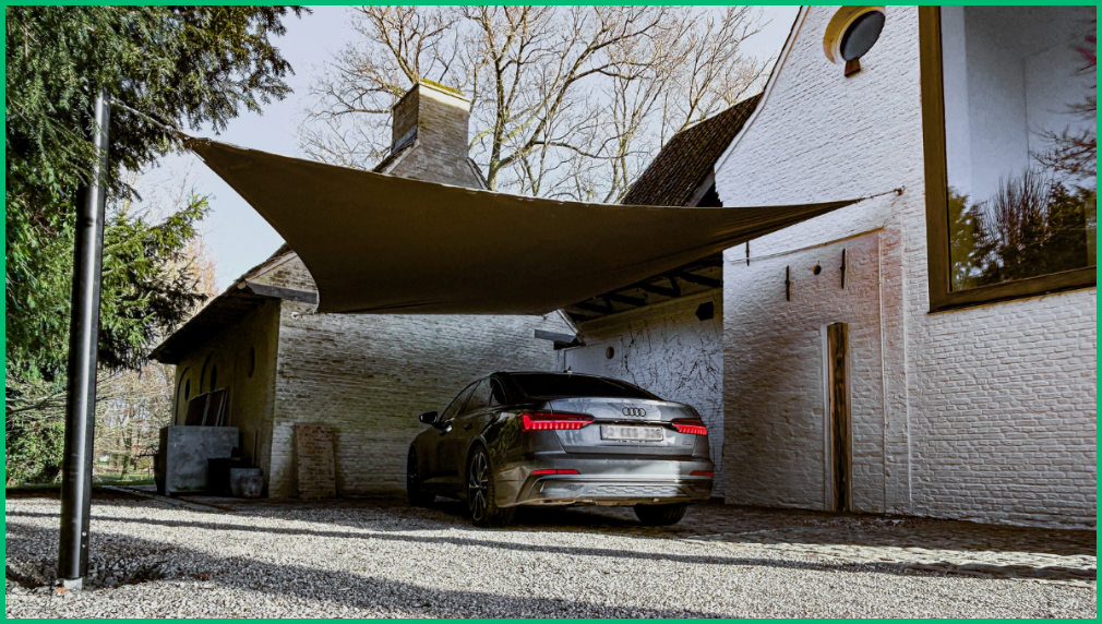 Donkere Audi geparkeerd onder een carport overkapping met tentdoek bij een bakstenen muur