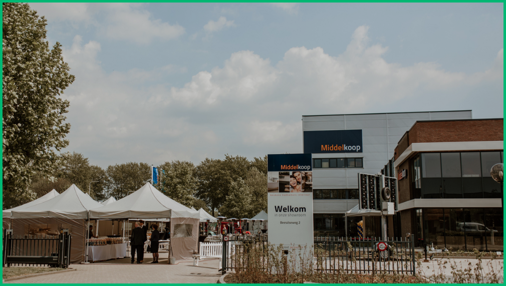 Witte pagodatenten opgesteld bij een bedrijfsevenement met Welkom bord op parkeerterrein