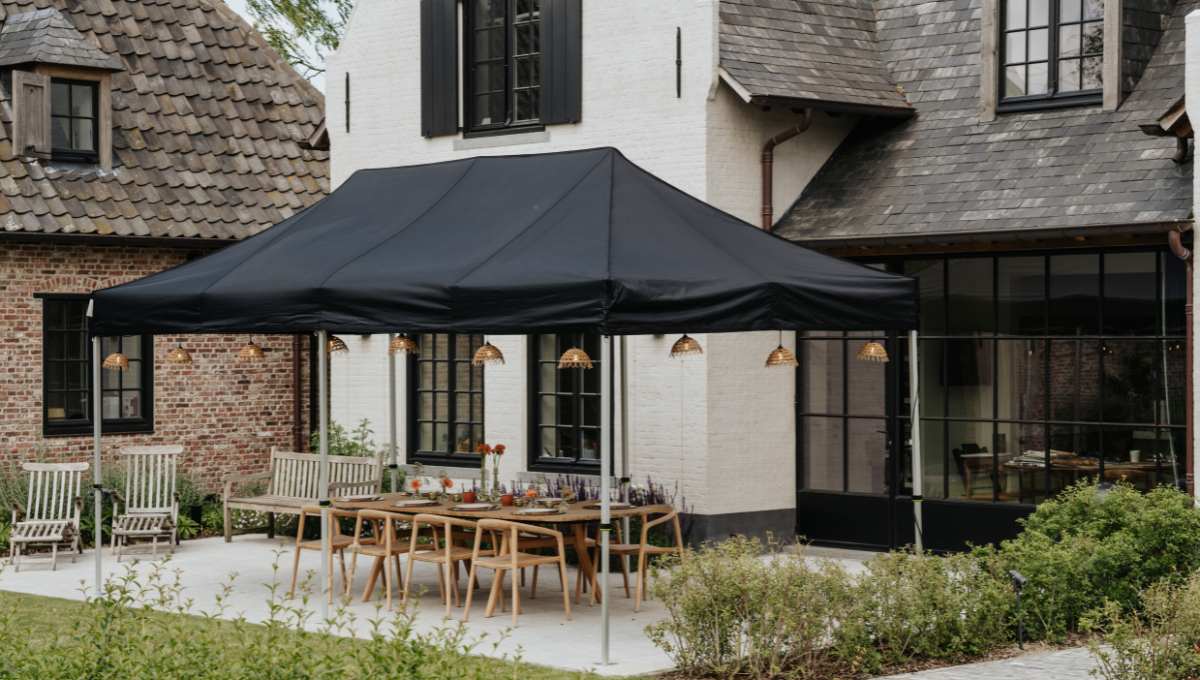 Zwarte vouwtent opgesteld op een terras voor een buitenetentje.