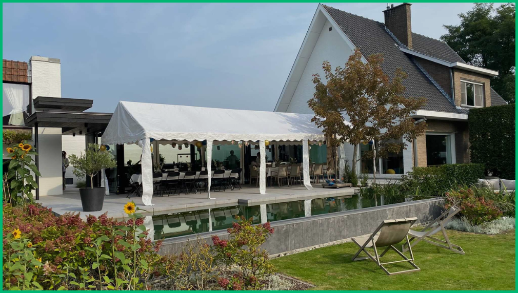 Grote witte partytent naast een landhuis met tuin en zonnebloemen voor vergelijking partytent versus vouwtent